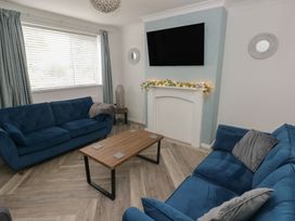 A living room with blue sofas and a coffee table at Cwtch Ar Y Mor in Burry Port