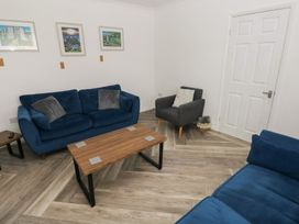 A living room with a blue sofa and wooden coffee table at Cwtch Ar Y Mor Burry Port