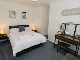 A bedroom with a bed and a dressing table at Cwtch Ar Y Mor in Burry Port