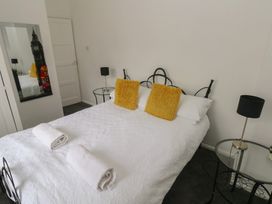 A bedroom with a bed, pillows, towels, mirror, and lamps at Cwtch Ar Y Mor in Burry Port