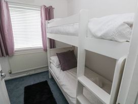 A bedroom with a bunk bed and curtains at Cwtch Ar Y Mor Burry Port