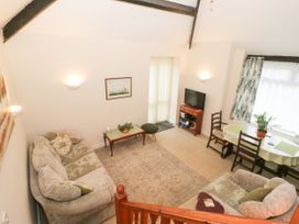 A living room with sofas a coffee table a television and a dining table with chairs at The Old Coach House in Penmaenmawr