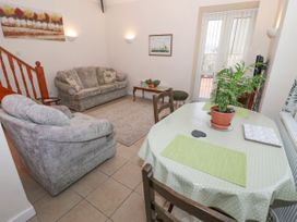 A living room with two sofas a coffee table a dining table with a plant and chairs and glass doors at The Old Coach House in Penmaenmawr