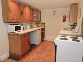 A kitchen with wooden cabinets a microwave refrigerator stove and sink at The Old Coach House in Penmaenmawr