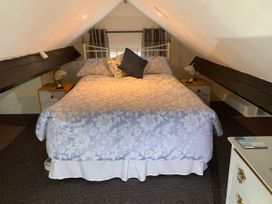 A bedroom with a double bed under a slanted ceiling with nightstands and lamps at The Old Coach House in Penmaenmawr