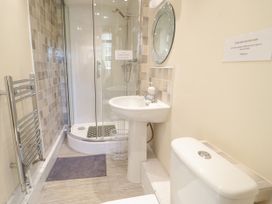 A bathroom with a shower, sink, mirror, towel rack, and toilet at The Old Coach House in Penmaenmawr