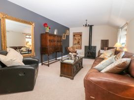 A living room with a leather sofa and armchair wooden cabinets a coffee table and a wood stove at 1 Church Barns in Pocklington