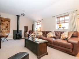 A living room with a brown leather sofa and a wood-burning stove at 1 Church Barns in Pocklington