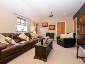 A living room with brown leather sofa black armchair wooden coffee table and framed pictures on the wall at 1 Church Barns in Pocklington
