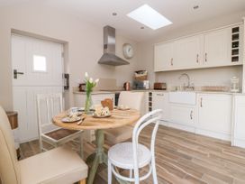A kitchen with white cabinets a wooden round table with chairs and food on it at 1 Church Barns in Pocklington
