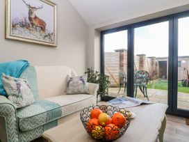 A living room with a patterned sofa a coffee table with a fruit bowl and large glass doors leading to a garden at 1 Church Barns in Pocklington