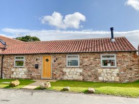 A single-story house with a tiled roof and brick walls with stone accents in front of a lawn at 1 Church Barns in Pocklington