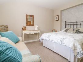 A bedroom with a bed sofa and a dressing table with a mirror at 1 Church Barns in Pocklington