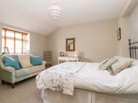 A bedroom with a bed sofa and a desk with a mirror on the wall at 1 Church Barns in Pocklington