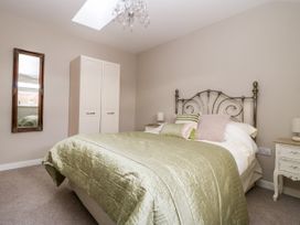 A bedroom with a bed green bedspread pillows two bedside tables a wardrobe a wall mirror and a chandelier at 1 Church Barns in Pocklington