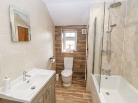 A bathroom with a toilet sink with hand soap and bathtub with shower at 1 Church Barns in Pocklington