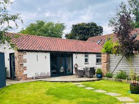 A backyard with lawn stone path patio table and chairs and a building with tiled roof at 1 Church Barns in Pocklington