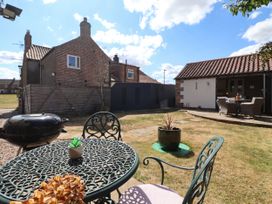 A garden with a table, chairs, and a grill at 1 Church Barns Pocklington