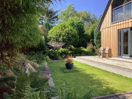 A garden with a patio, chairs, and trees at Larchwood Lodge in Ellon