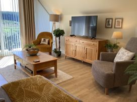 A living room with a television and an armchair at Larchwood Lodge in Ellon