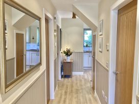 A hallway with a mirror and a table with a vase at Larchwood Lodge in Ellon
