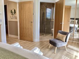 A bedroom with a shower and a chair at Larchwood Lodge in Ellon