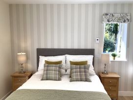 A bedroom with a bed and two bedside tables at Larchwood Lodge in Ellon