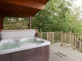 A hot tub on a wooden deck surrounded by trees at Sunny View in Rhayader