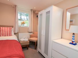 A bedroom with a bed, wardrobe, chair, and lamp at Lanapoule Salcombe