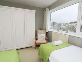 A bedroom with a bed, wardrobe, and chair at Lanapoule in Salcombe