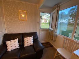 A snug room with a sofa, cushions, and a window at 246 California Road, California, Norfolk