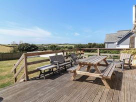 An outdoor seating area with a table and chairs at Auverne Poundstock near Widemouth Bay