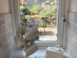 A kitchen with mugs on a holder and a view of a garden at 3 Lowerbourne Terrace in Porlock