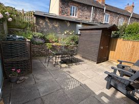 A garden with a table, chairs, and a shed at 3 Lowerbourne Terrace in Porlock