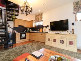 An open plan living room and kitchen with a spiral staircase at The Coach House, The Grove Combe Martin