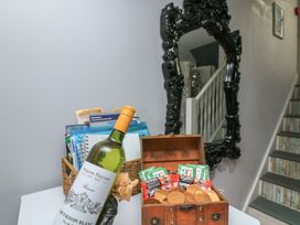 A hallway with a wine bottle and a wooden box filled with snacks at Hidden Treasure in Brixham