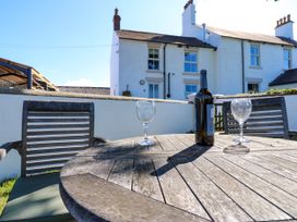 An outdoor table with a wine bottle and glasses at Tight Lyne Cottage in Longtown