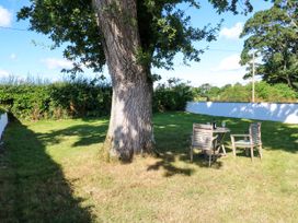 A garden with a tree and outdoor furniture at Tight Lyne Cottage in Longtown