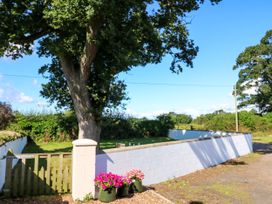 A garden with a tree and flower pots at Tight Lyne Cottage in Longtown