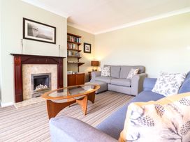 A living room with a fireplace and bookshelf at Castle Cove in Abergele