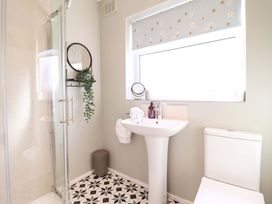A bathroom with a shower, sink, toilet and mirror at Castle Cove, Abergele