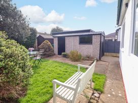 A garden with a shed, table, and chairs at Castle Cove in Abergele