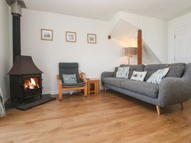 A living room with a wood stove and seating at Pilchard Cottage in Sennen Cove