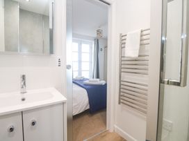 A bathroom with a sink and mirror leading to a bedroom at Pilchard Cottage Sennen Cove