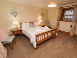 A bedroom with a bed, nightstand, chair and window at Stable D'or in Embleton