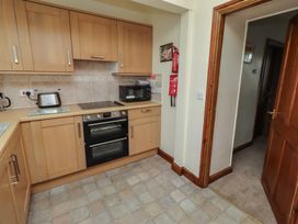 A kitchen with cabinets, stove, microwave and kettle at The Retreat in Embleton