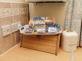 A wooden tray with bread and treats in a kitchen at The Retreat in Embleton