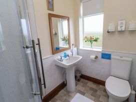 A bathroom with a sink, toilet, shower, and window at The Retreat in Embleton