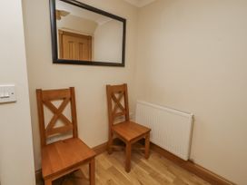 A hallway with two wooden chairs and a mirror at Low Croft in Embleton