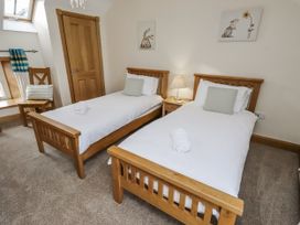 A bedroom with twin beds and a bedside lamp at Low Croft in Embleton